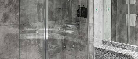 Un baño moderno con ducha acristalada, inodoro blanco y encimera de granito.