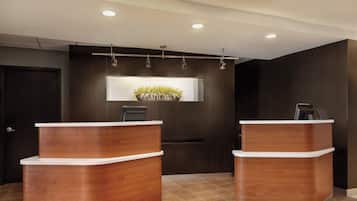 A reception area with two wooden reception desks, a dark wall, and a potted plant on the wall.