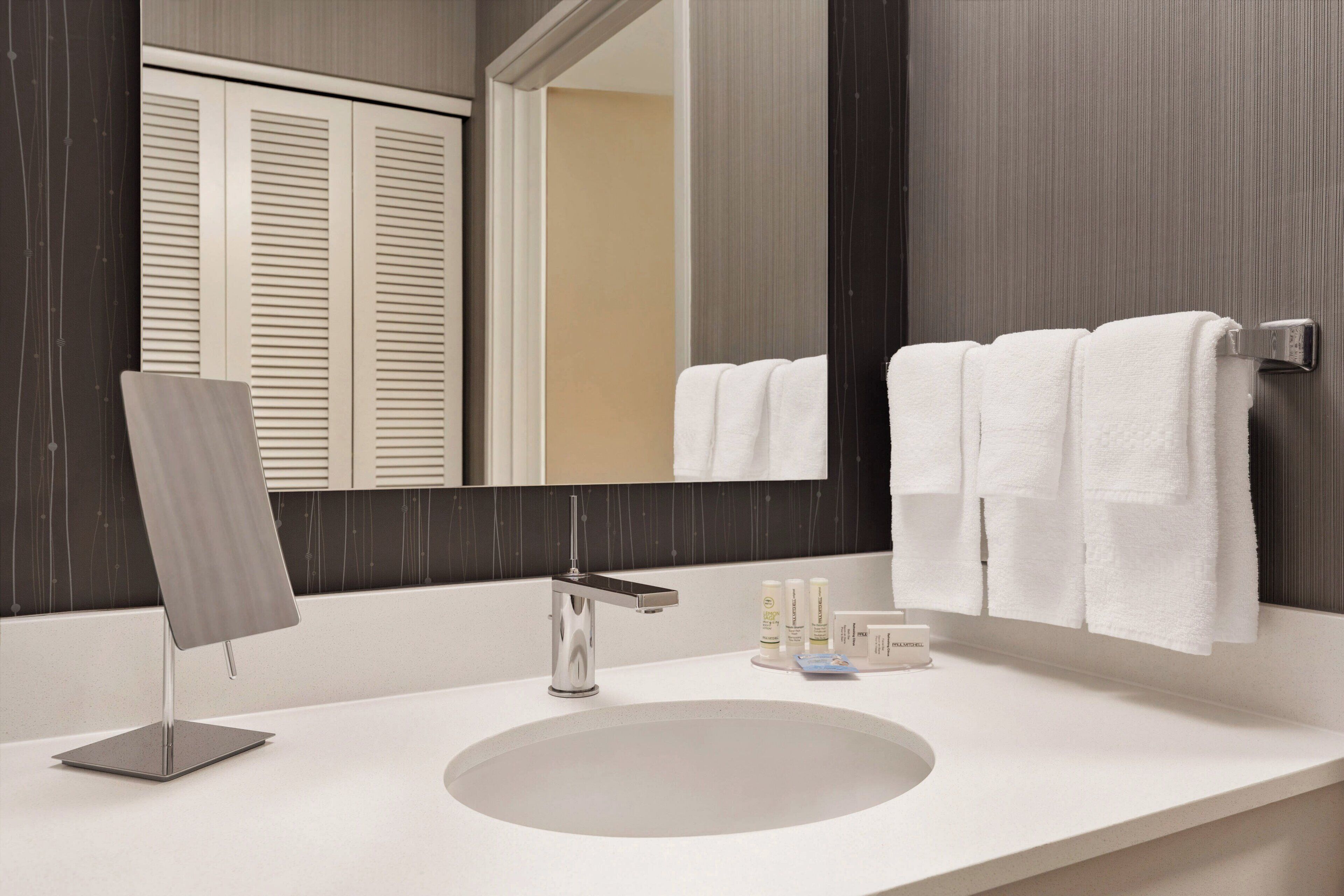A modern bathroom with a large mirror, a sink, and a towel rack.