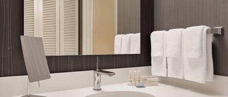 A modern bathroom with a large mirror, a sink, and a towel rack.