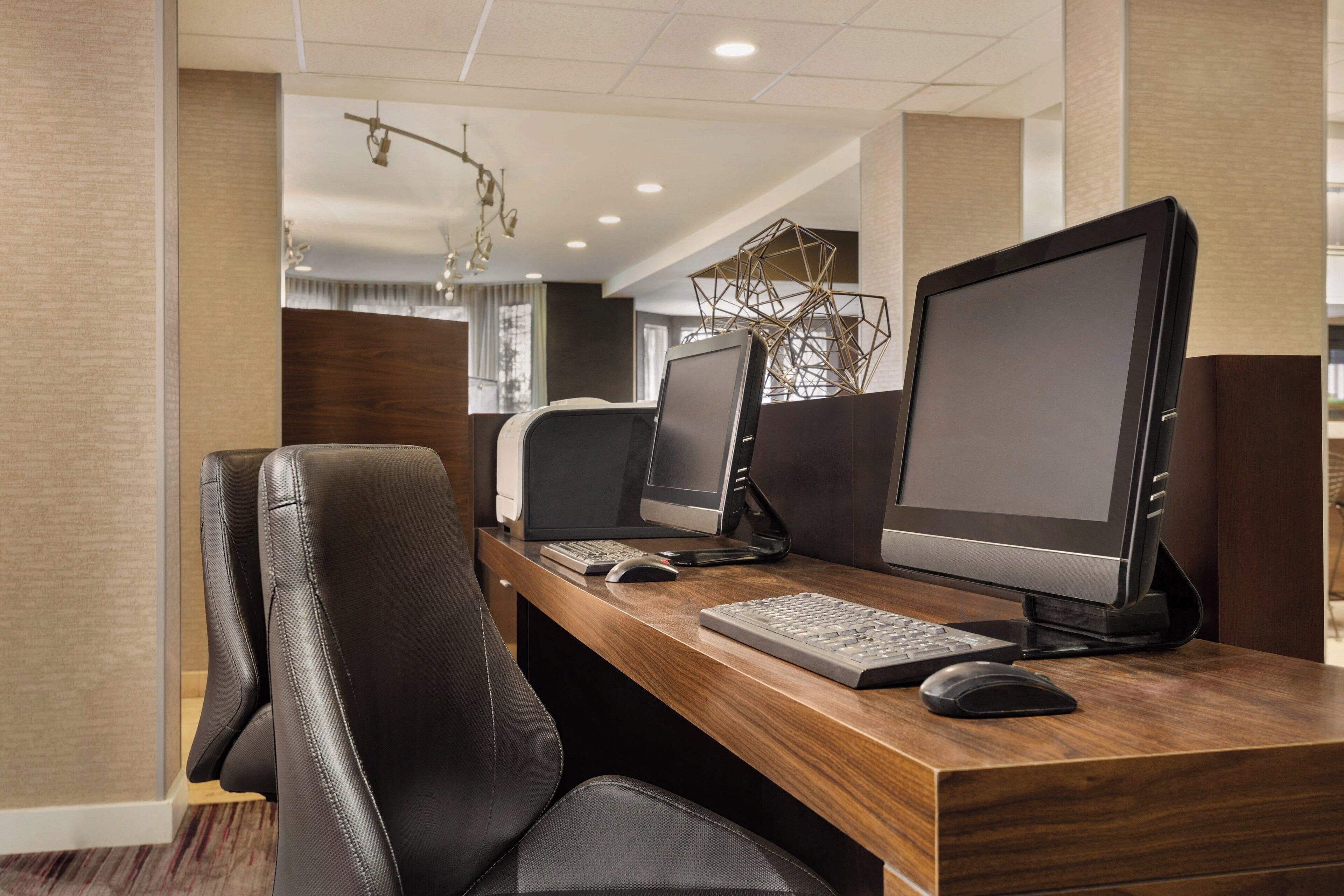 A modern office space with two desks, each equipped with a computer monitor, keyboard, and mouse.