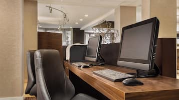 A modern office space with two desks, each equipped with a computer monitor, keyboard, and mouse.