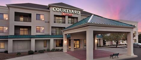 Un hotel Courtyard Marriott con una entrada cubierta, varios balcones y un sendero de ladrillo rojo.