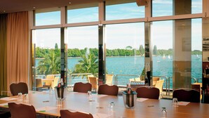 A conference room with a large table, chairs, and a view of a lake with boats. - Courtyard by Marriott Hannover Maschsee (Hannover)