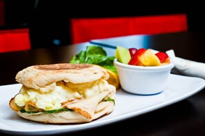 A sandwich with a side of fruit salad on a white plate.