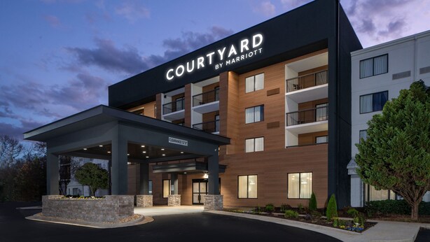 A Courtyard by Marriott hotel with a covered entrance, multiple balconies, and a landscaped area.