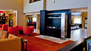 A modern lobby with red seating, a reception desk, and a staircase.