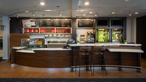 A modern bar area with a wooden counter, stools, and a menu board.