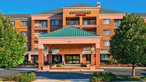 Un hotel Courtyard by Marriott con fachada de ladrillo, varios balcones y techo verde.