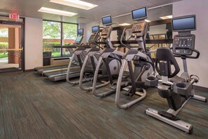 A fitness center with treadmills and elliptical machines, a carpeted floor, and a large window providing a view of the outdoors. - Courtyard by Marriott Dulles Town Center (Sterling)