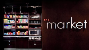 Una cocina con estantes llenos de aperitivos, un microondas y un letrero en la pared que dice "the market".