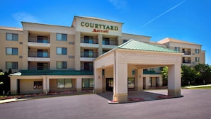 Un hotel Courtyard Marriott con entrada techada y estacionamiento.