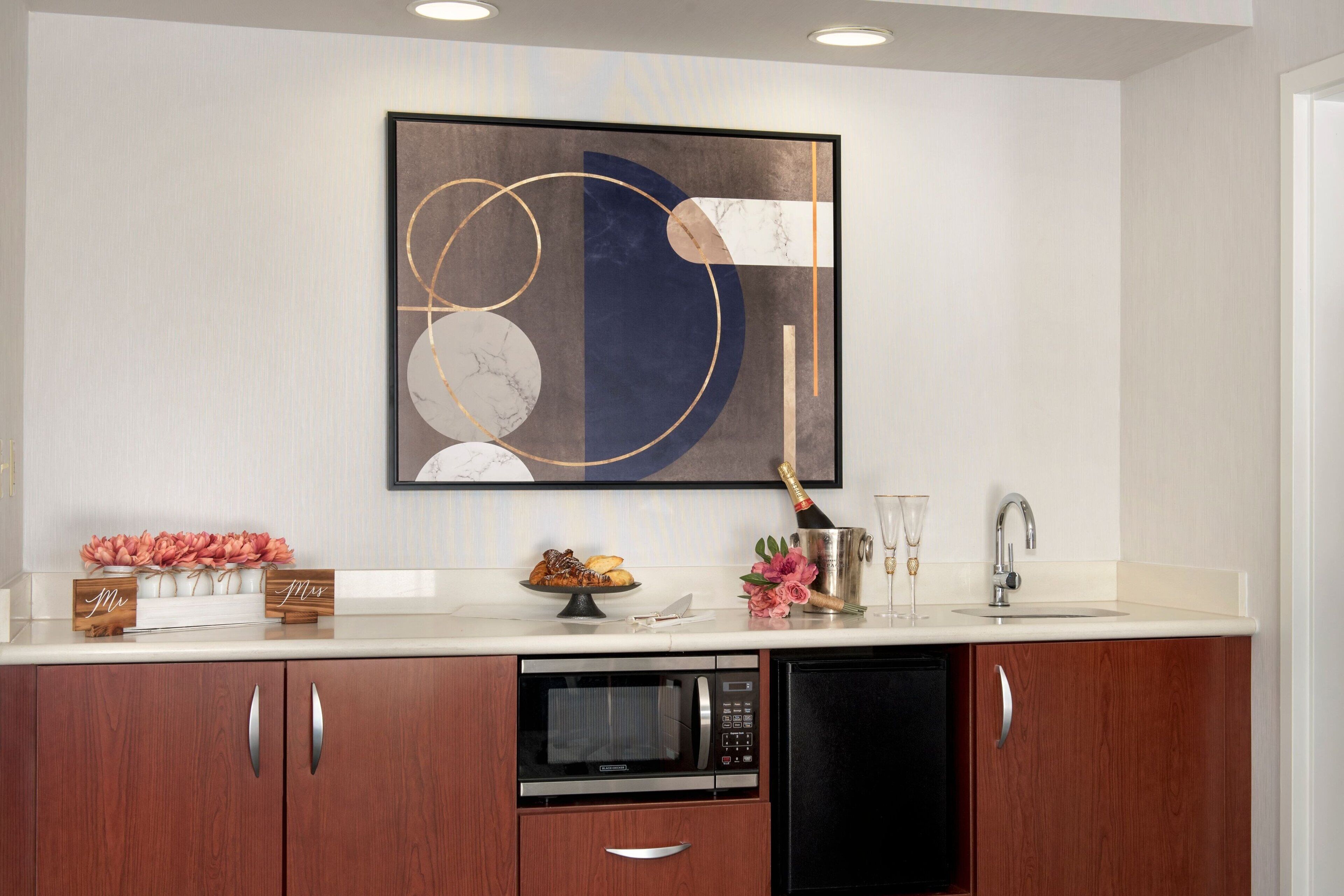 A modern kitchen with a marble backsplash, a large abstract painting, and wooden cabinets.