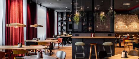 Un interior de restaurante moderno con mesas de madera, sillas coloridas y lámparas colgantes.