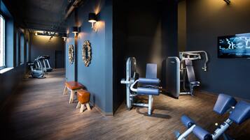 A gym with exercise equipment, a bench, and wall-mounted lights.