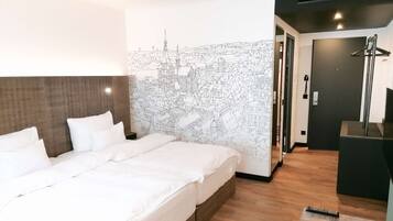 A hotel room with a large bed, a headboard, a wall mural, a shower area, and a desk.