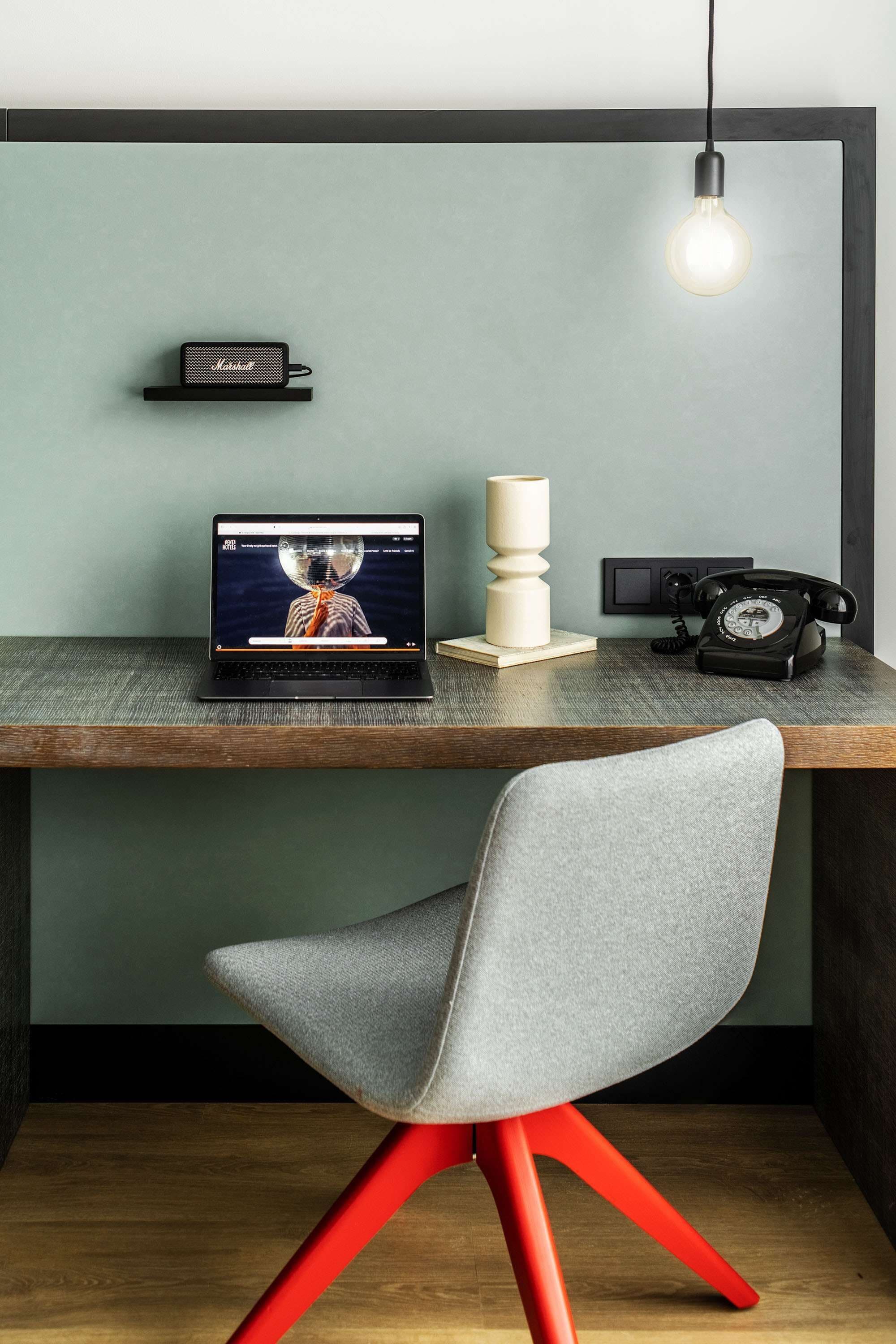 Ein moderner Arbeitsplatz mit einem Laptop, einem Vintage-Telefon und einer Lampe auf einem Holztisch.