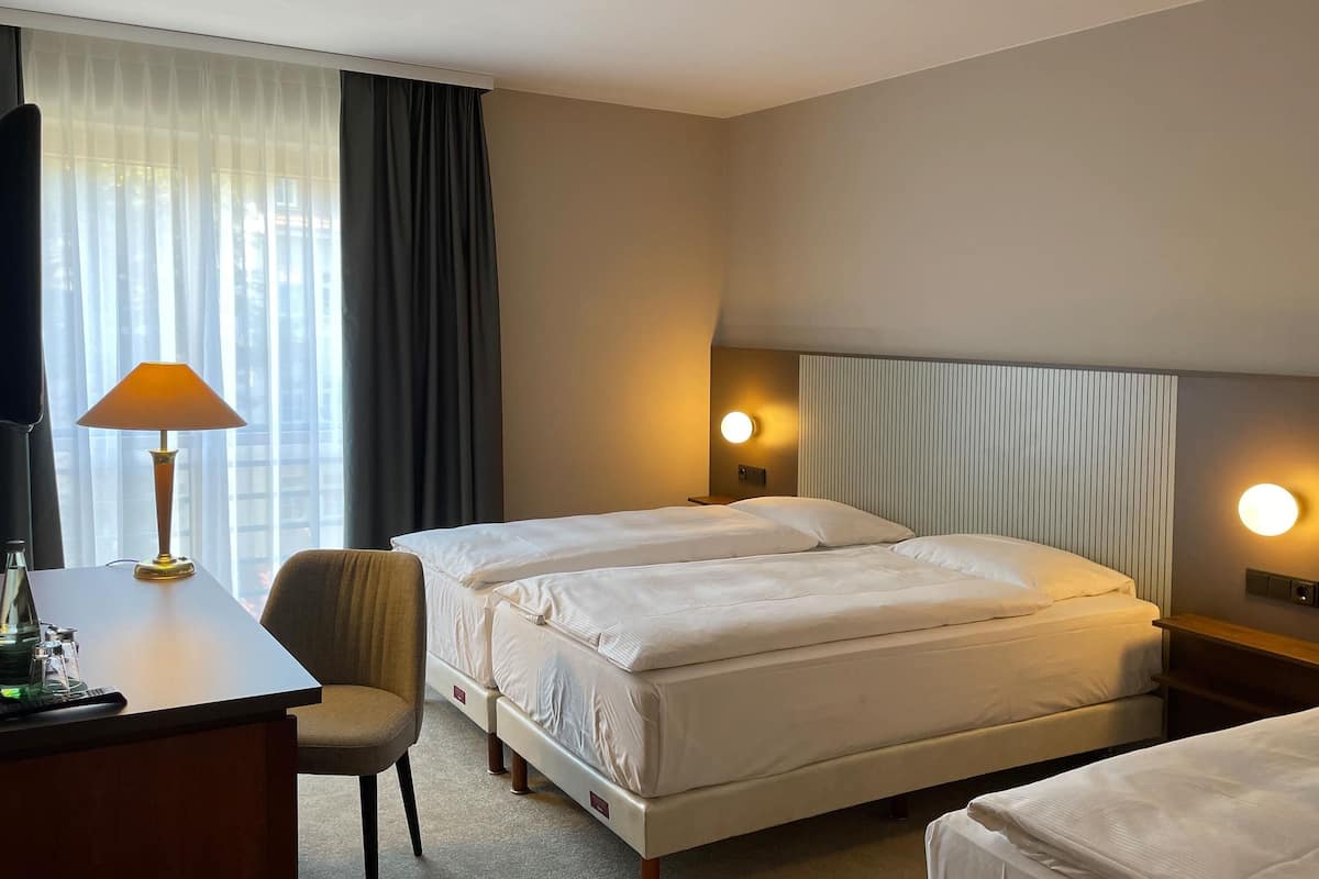 A hotel room with two beds, a desk, a chair, and two bedside lamps.