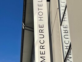 A building with vertical signage reading 'MERCURE HOTEL' and 'MERCURE HOTEL' in a different language.