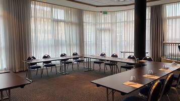 Una sala de conferencias con una larga mesa, sillas y suelo alfombrado.