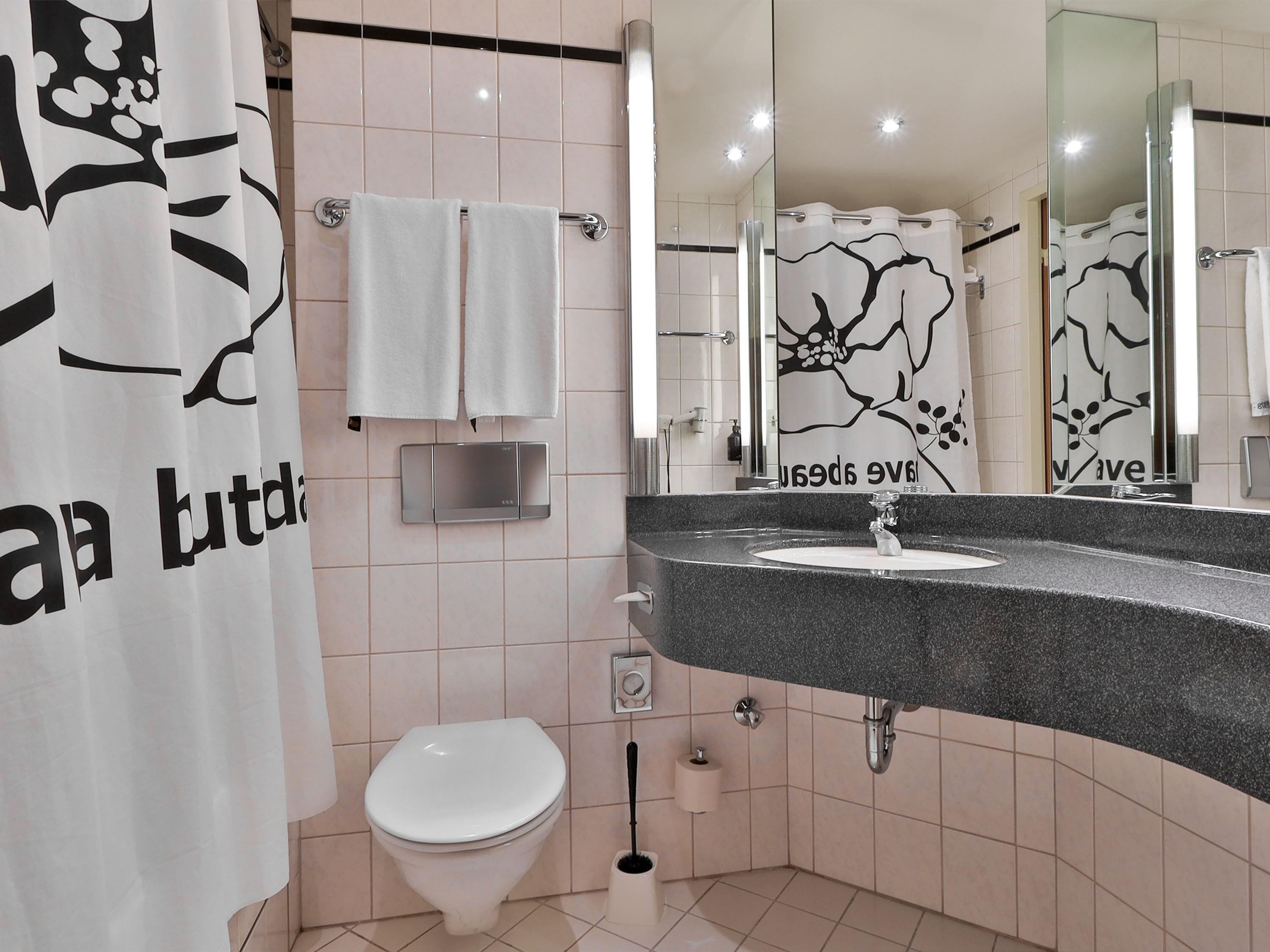 A bathroom with a toilet, sink, and a shower area.