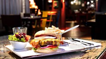 Ein Essen mit einem Burger, Pommes und einem Salat auf einem Tisch in einem Restaurant.