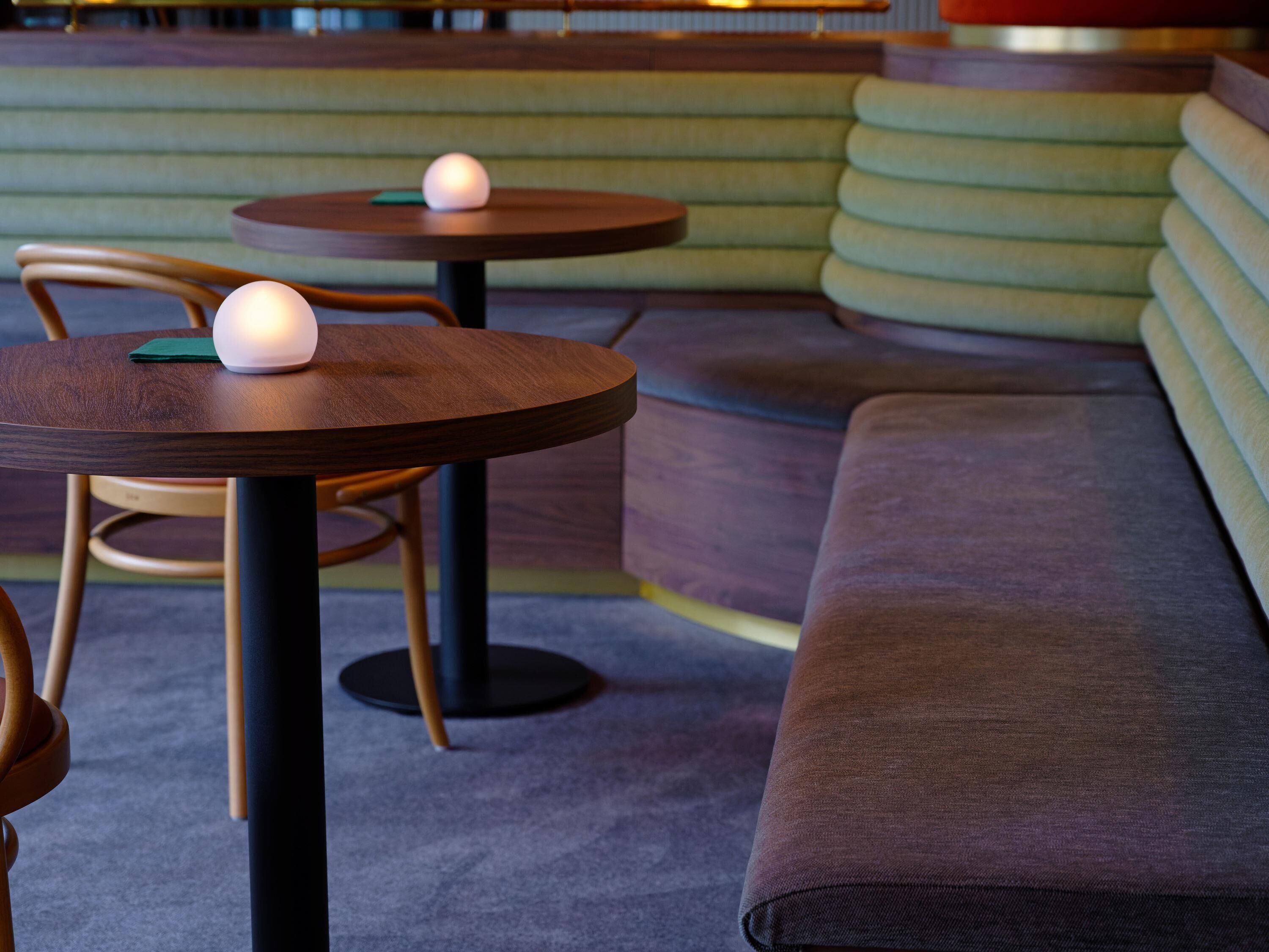A seating area with round tables and cushioned benches.