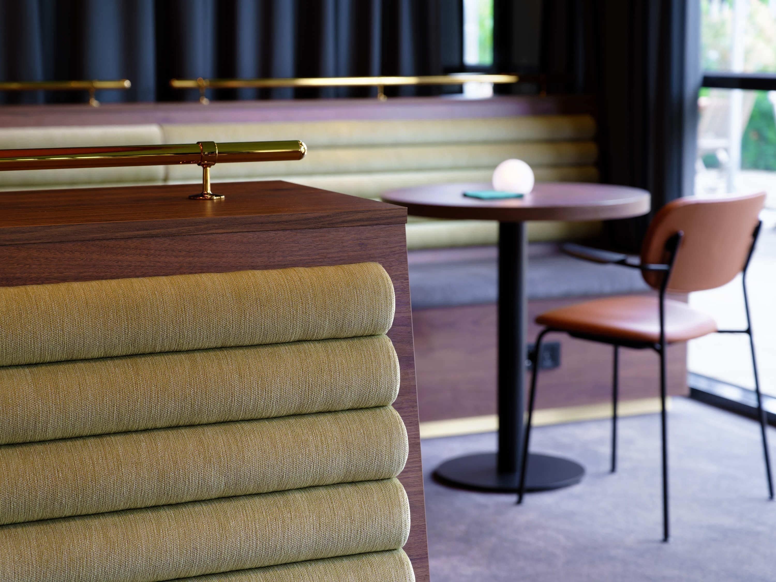 Ein modernes Interieur mit einer Holztresen, gepolsterten Sitzgelegenheiten und einem runden Tisch.