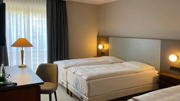Une chambre d’hôtel avec deux lits, un bureau, une chaise et deux lampes de chevet.