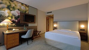 Une chambre d’hôtel équipée d’un lit, d’un bureau, d’une chaise, d’une télévision et d’une lampe fixée au mur.