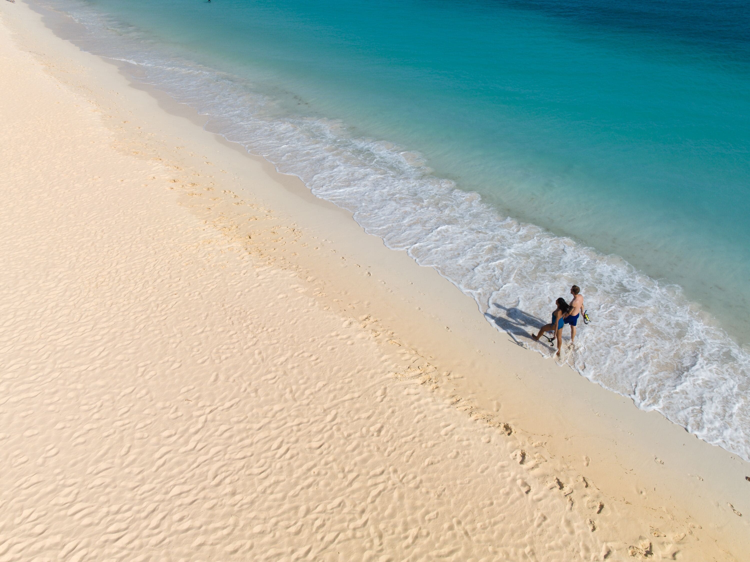 Une plage à l’eau turquoise et limpide, bordée d’un rivage sablonneux.