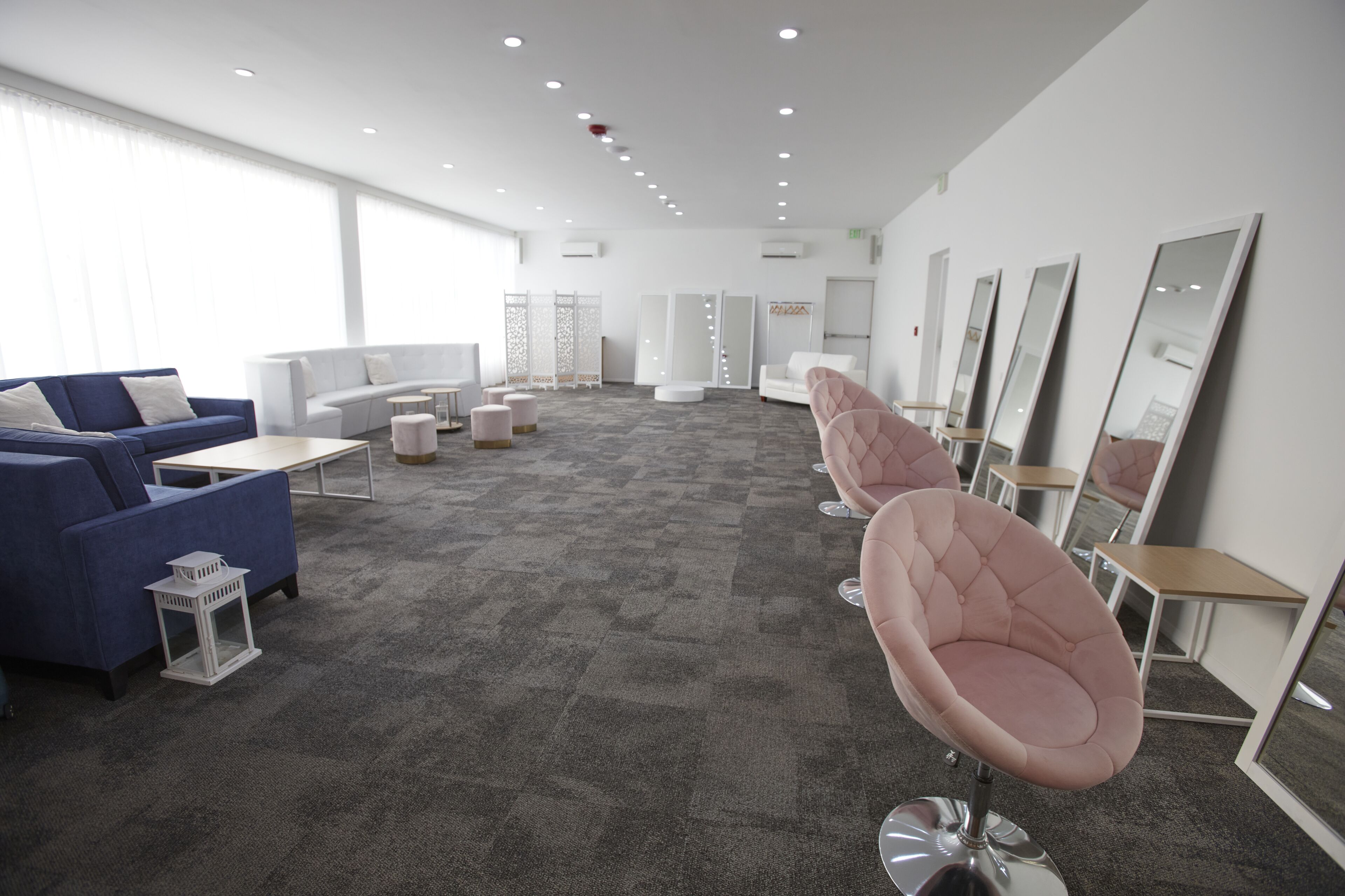 Eine moderne Hotelhalle mit einem blauen Sofa, weißen Sesseln und einer großen Spiegelwand.
