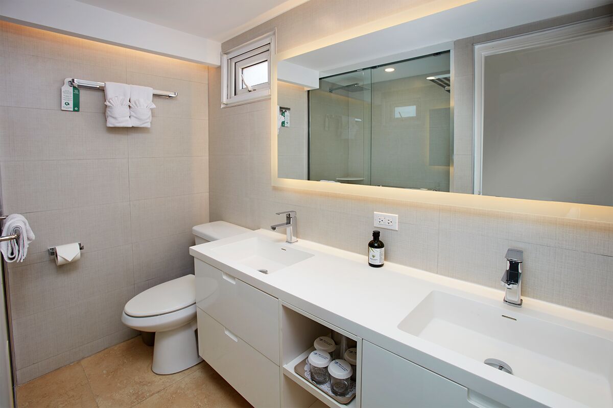 Un baño moderno con un lavamanos blanco, inodoro y cabina de ducha de vidrio.