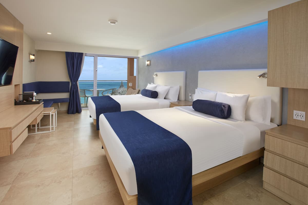 Ein modernes Hotelzimmer mit zwei Betten, einem Schreibtisch und Blick auf den Ozean.
