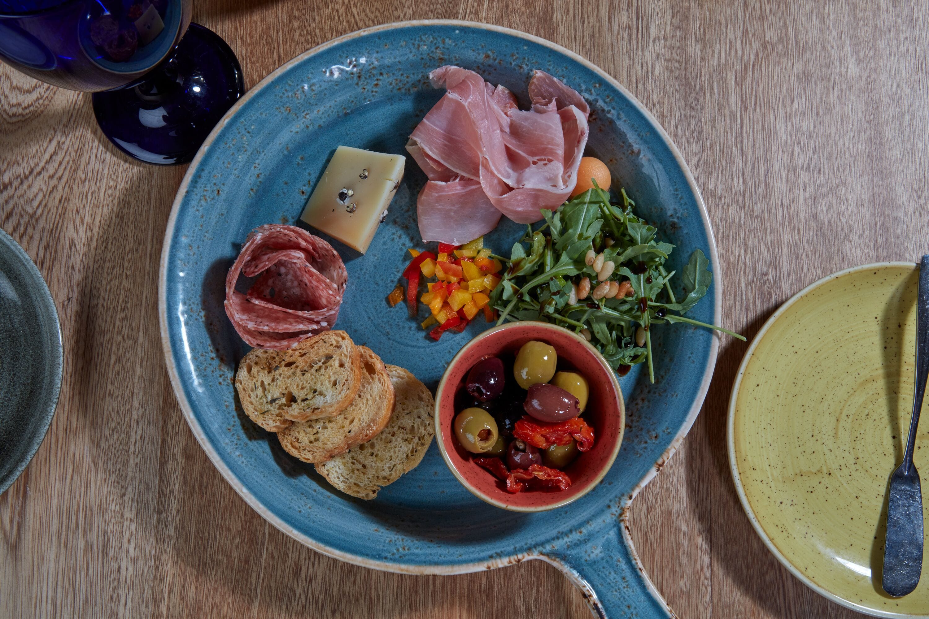 A plate with various food items including bread, olives, and greens.