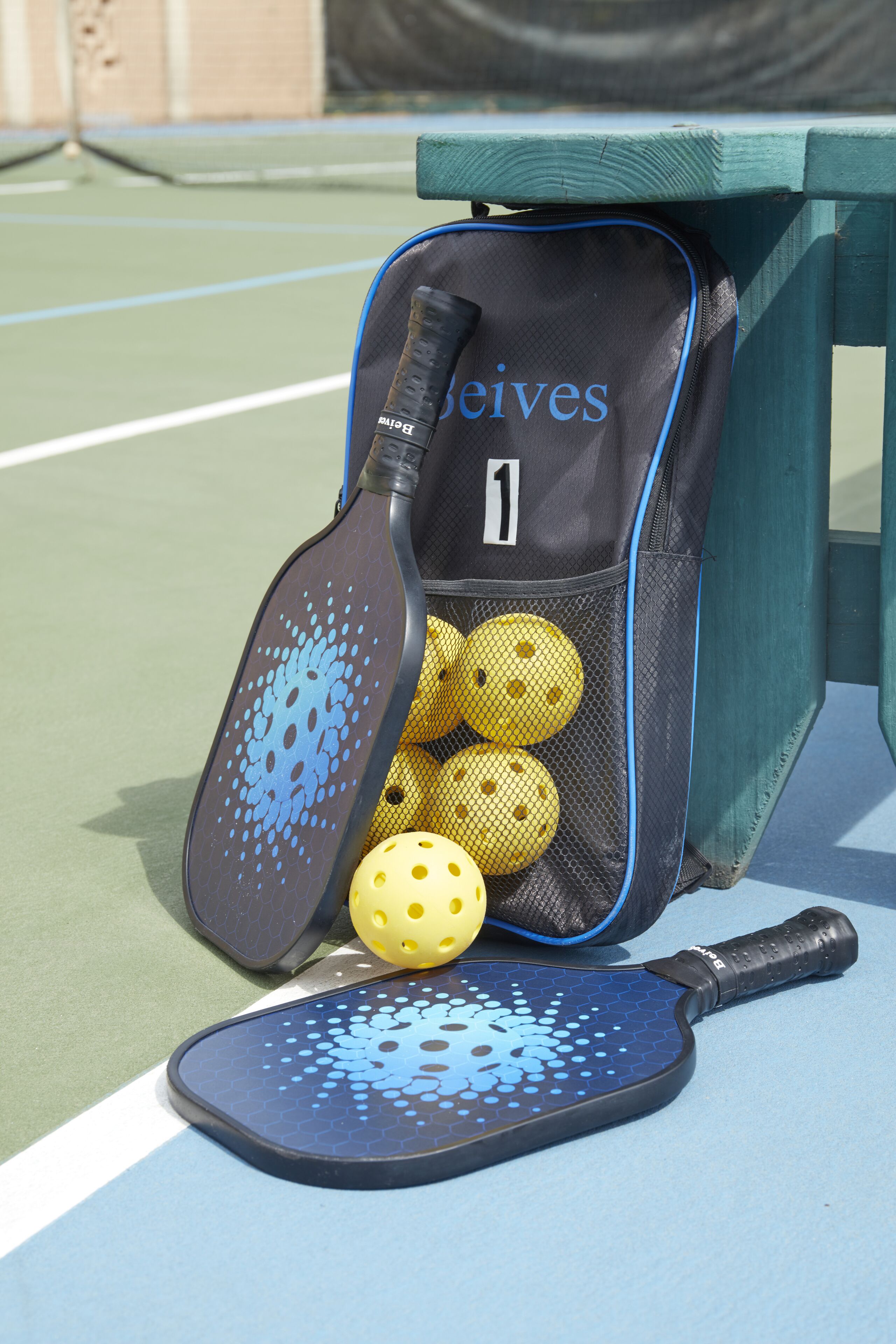 A tennis bag with a racket and tennis balls on a tennis court.