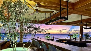 Eine Bar mit Meerblick, Holzbalkendecke und Topfpflanzen.
