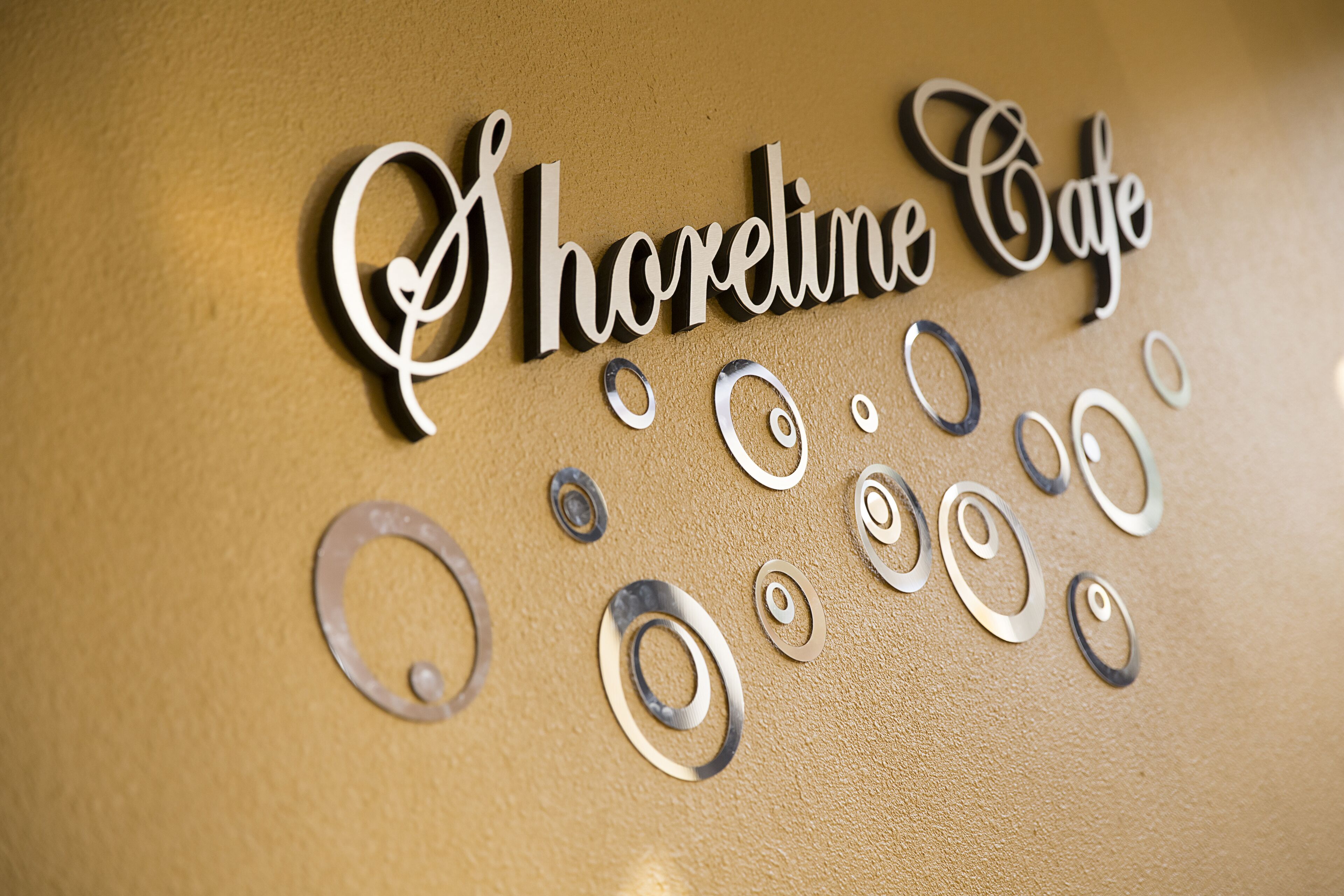 Eine Wand mit dem Schriftzug "Shoreline Cafe" und dekorativen Metallschwungen.