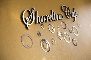 A wall with the text "Shoreline Cafe" and decorative metal swirls. - Grande Shores Ocean Resort (Myrtle Beach)
