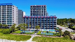 A multi-story hotel with balconies, a swimming pool, and a well-maintained lawn with lounge chairs. - Grande Shores Ocean Resort (Myrtle Beach)