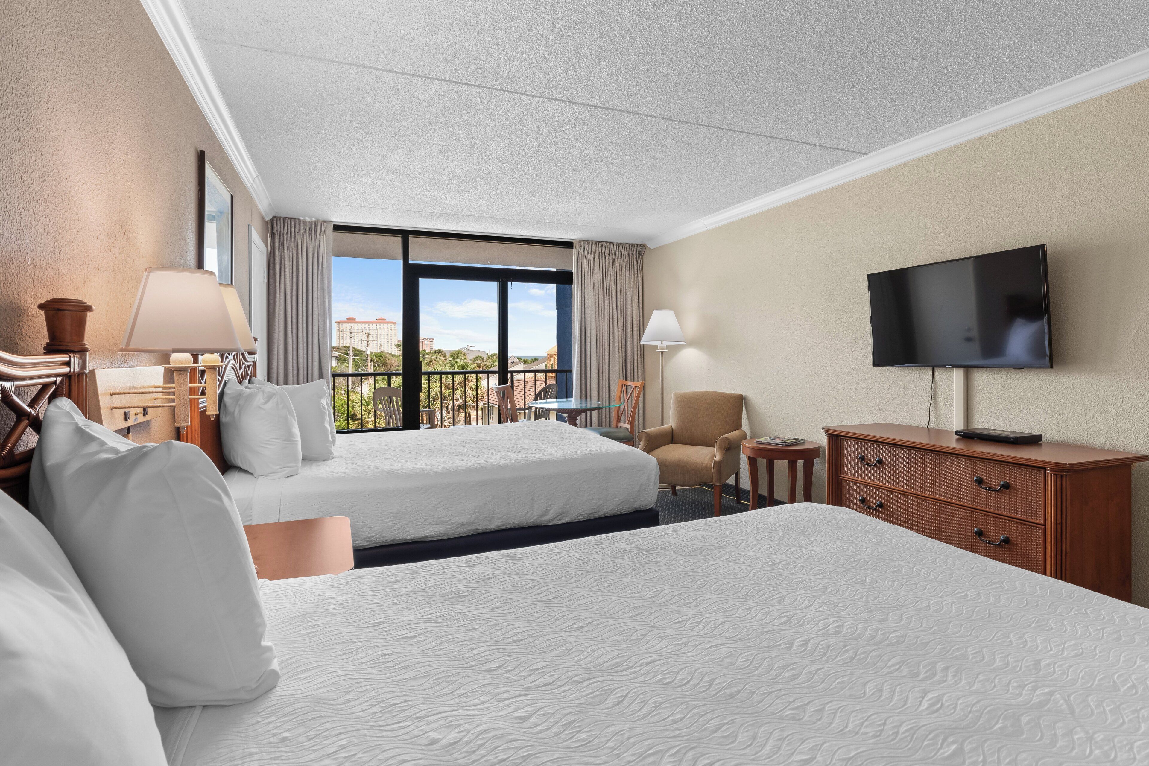 A hotel room with two beds, a TV, a desk, and a chair.