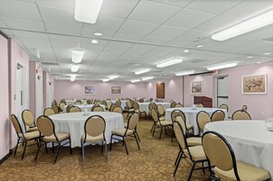 A conference room with multiple round tables, chairs, and ceiling lights.