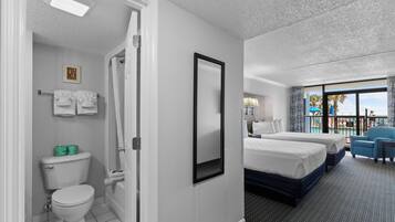 Habitación de hotel con baño, dos camas, balcón con vistas y un ventanal grande.