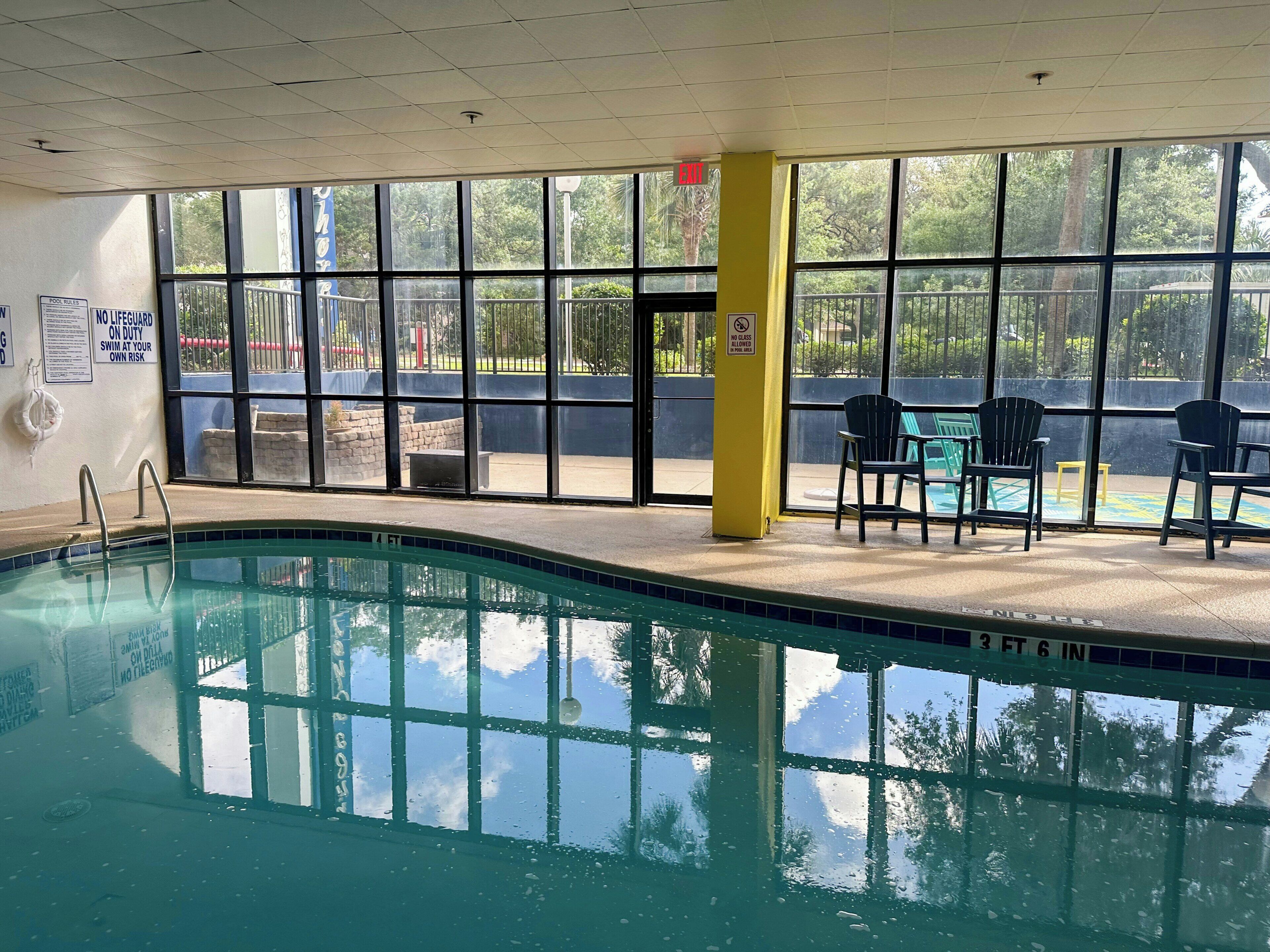 Ein Hallenbad mit großen Glaswänden, einem Rettungsschwimmerstuhl und einer gelben Säule.