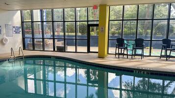Ein Hallenbad mit großen Glaswänden, einem Rettungsschwimmerstuhl und einer gelben Säule.