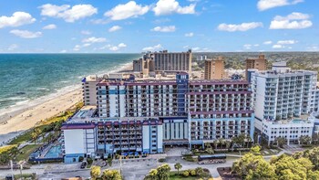 A beach resort with a swimming pool, lounge chairs, and beach umbrellas. at Grande Shores Ocean Resort