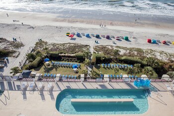 Outdoor round tables with white chairs, set up for an event by the beach. at Grande Shores Ocean Resort