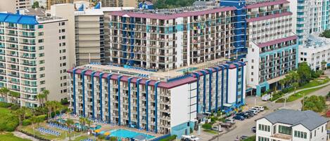 Un hotel de varios pisos con balcones, piscina y estacionamiento.