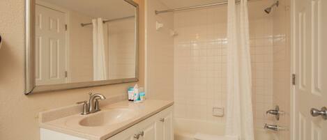 A bathroom with a sink, mirror, and shower.