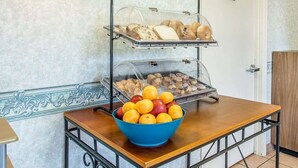 A buffet setup with two glass-covered trays of food, a bowl of oranges, and a sign indicating the area is for employees only. - Econo Lodge Dothan West (Dothan)
